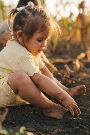 Baby girl playing on the ground standing with bare feet, dirty. Outdoor lifestyle. Happy family.の写真素材