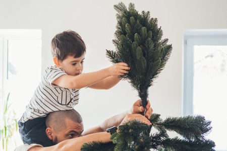 Father and son install an artificial Christmas tree. Natural xmas tree for merry winter holiday season.の写真素材