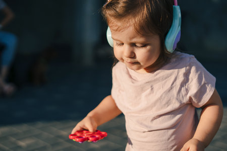 The baby girl spent time outside in the open air, wearing earplugs to keep from catching a cold. Toddler playing. Summer or autumn dayの写真素材