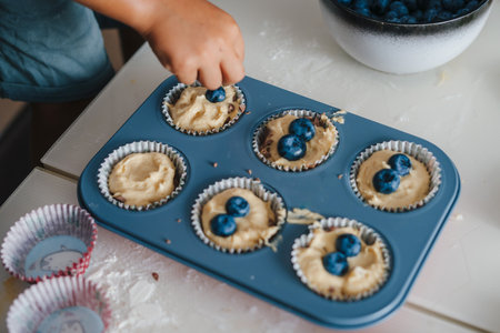 Close-up view of childrens hands decorating the still raw muffins before putting them in the oven. Sweet pastries, muffin, cupcake with cream. Holiday elementsの写真素材