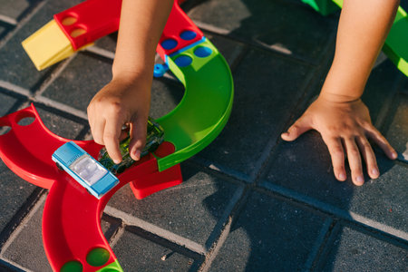 Close-up view of a little boy's hands playing with colorful plastic construction blocks at home backyard, sitting on the floor. Creative games for kids. Summer outdoor fun activity. Little garden. Home garden.の写真素材