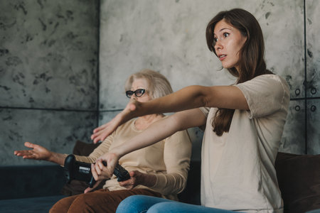 Dissatisfied woman expressing her disappointment that she lost in front of her mother. Technology and lifestyle concept. Entertainment at home, have fun in spare time.の写真素材