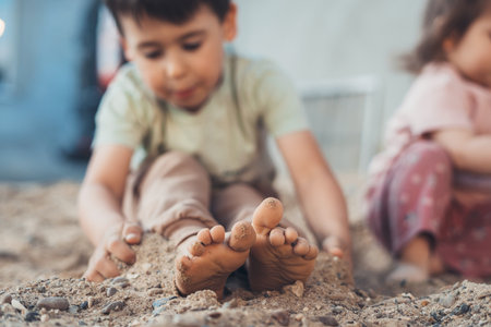 Couple of sibling children playing in sand sitting on summer country garden ground. Rustic portrait. Nature summer. Friends play. Happy family.の写真素材