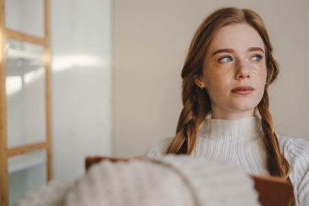 Woman sitting on sofa covered with a blanket writing in notebook. A cozy way of life .の写真素材