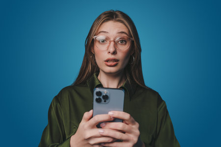 Shocked woman reacting on sms frustrating on mobile phone, complaining on smartphone text, standing...