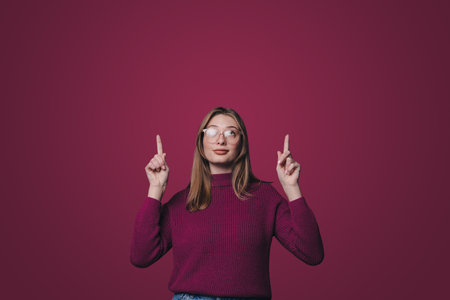 Portrait of beautiful young woman pointing up two hands with finger on upper side with smile faceの写真素材