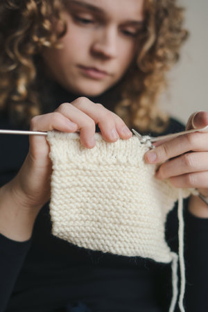 Concentrated creative woman knitting scarf and wearing cozy sweater. Focus on hands. Hobby courses or workshops for learning knitting. Stay home activity, quarantine concept.の写真素材