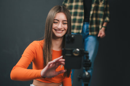 Couple in cozy clothes recording a dance video at home isolated over black background. Performing for funny viral and active video for social media app.の写真素材