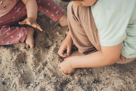 Top view of the hands of some children digging in the stony sand from the back of the house from the village. Summer vacation. Creative concept. Little garden.の写真素材