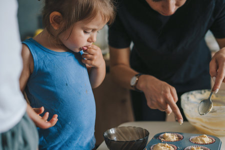Mom and her little kids cooking muffins in kitchen, enjoying preparing homemade pastry. Family, cooking, baking and people concept.の写真素材