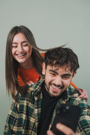 Caucasian man and woman influencers recording live video camera standing against gray wall background. Vlogger selfie shoot enjoy work show smile teach like share app. Video live streaming.の写真素材
