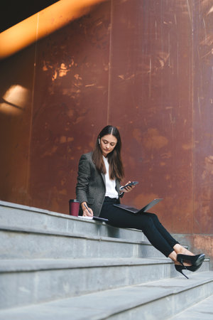 Photo of charming young woman assistant enjoying fresh air while working outdoors on a laptop connected to public wifi. Wireless communication. Woman relaxing. Online communication. Sitting woman outdoors.の写真素材