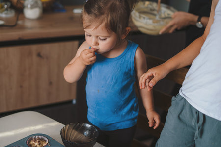 Cute little baby girl and her brother spooning muffin batter into the baking cups, baking at home. Family education. Family concept.の写真素材