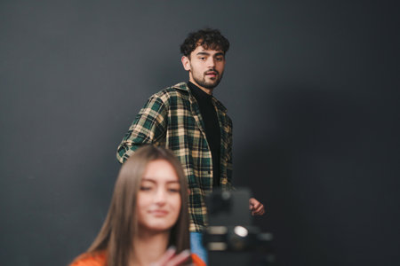 Joyful young couple with standing against black background filming video with mobile phone. Streaming video.の写真素材