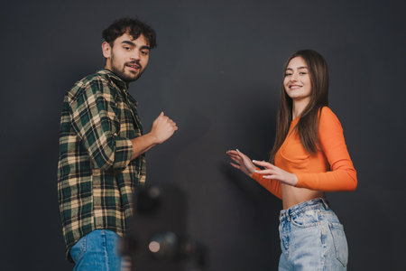 Blogger couple dancing together during making dance video challenge on smartphone isolated over black background. Video blogging. Creative girl and man of zoomer generation creating content for social networksの写真素材