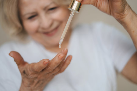 Close-up portrait person applying a drop of skin care liquid from pipette on her fingers. Skin care. Positive person. Facial beauty. Anti-aging cosmetic treatment.の写真素材
