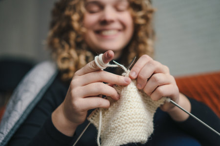 Happy positive curly-haired woman enjoying leisure time, holding needles, hobby. Domestic lifestyle. People lifestyle.の写真素材