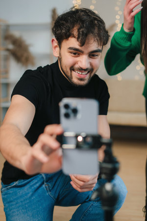 Blogger caucasian man live recording video on social network at home. Social media via mobile phones. People and technology, young woman at work as vlogger.の写真素材