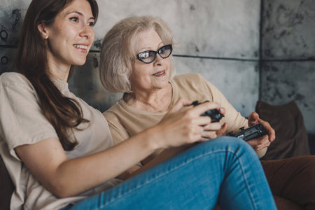 Positive young female in casual clothes and eyeglasses smiling and looking at camera while sitting on sofa and playing video gameの写真素材