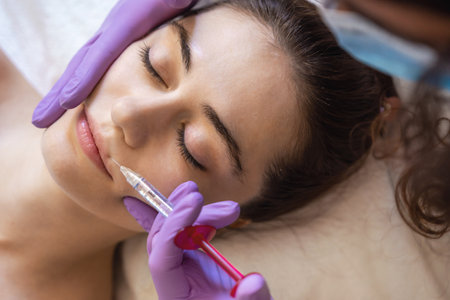 Close up of hands of cosmetologist making injection in female lips