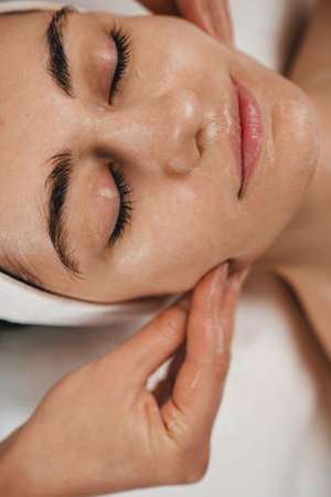 Young woman with closed eyes having a facial massage in spa salon.の写真素材