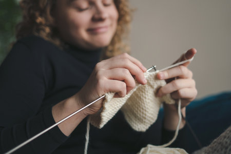 Close-up view of a womans hands knitting in cozy light. Crochet thick threads. Home comfort.