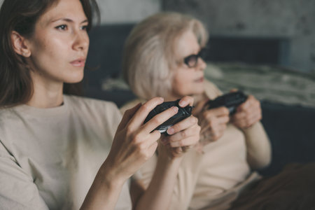 Two women playing console video games holding joystick controllers, emotional, gesture, reaction. Happy family. Computer entertainment.の写真素材
