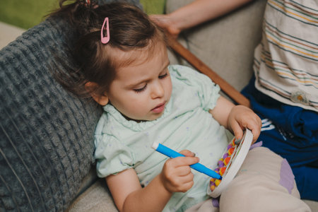 Playful little children siblings sitting on sofa drawing, resting on couch, family weekend pastime. People lifestyle portrait. Emotion expression. Home rest.の写真素材