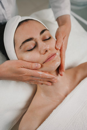 Beauticians hands applying foam cleanser for massaging clients face. Healthy skin care, exfoliation scrub soap with cleansing product. Skincare spa relax concept.の写真素材