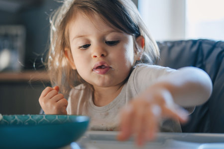 Cute little child with bowl of tasty yogurt in high chair at home.の写真素材
