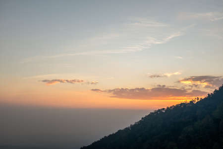 Sunset scene on hight mountain. Sunshine through the clouds. silhouette at the mountain.の写真素材