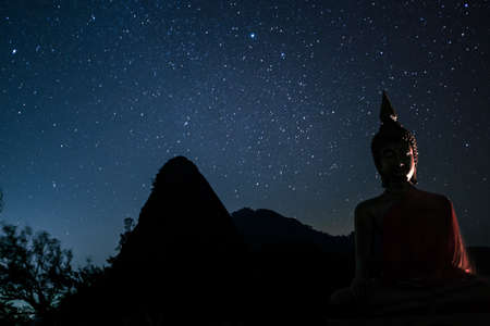 Night scape with beautiful stary sky and buddha image stand at the high mountain. Space background.の写真素材