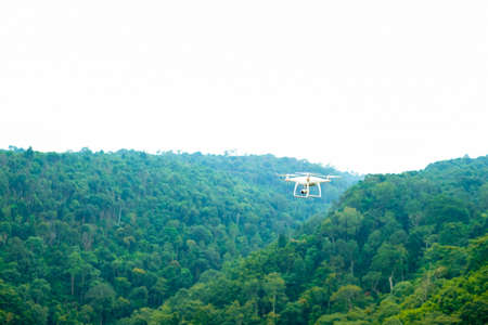 White drone flying over the green mountainの写真素材