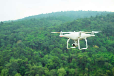White drone flying over the green mountain