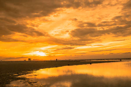 Golden scene on the beach at sunset. Group of tourists watching sunset at the coast.の写真素材
