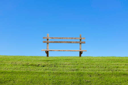 Old vintage bench on green grass at day, clear blue skyの写真素材