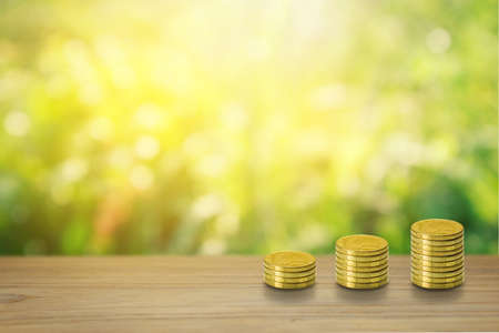 Stack of Coins, Financial, Business Saving and Interest increasing concept on teak wood and  natural green and bokeh with sunlight background.の写真素材