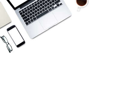Top view, Working desk, computer, laptop, smart phone, coffee, mug, glasses and notebooks on white background with copyspace for text.の写真素材