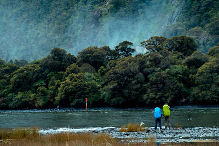 A couple backpacker enjoy with the stunning scene of the green nature and ford land at Milford Sound, New Zealandの写真素材
