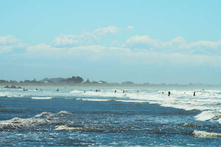 People enjoy their activities at the beautiful beach on a sunny blue sky day.