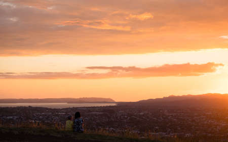Mom and son enjoy together their sunset over the mountain and the town.の写真素材