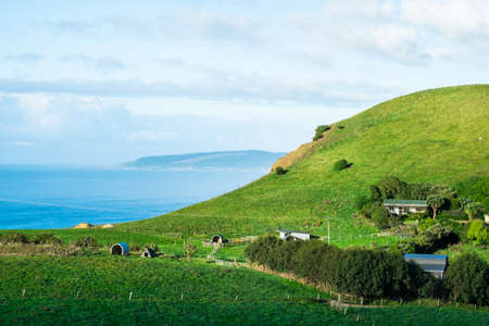 Stunning scene Cloudy and blue sky with farmland on the   green grassland beside the ocean. New...