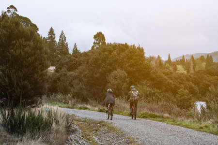 A couple traveler enjoy cycling on the gravel road beside the lake in cloudy day during winter season.の写真素材