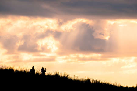 Silhouette scene of a couple enjoy with their drone at sunset on the top of Mt. Eden, Auckland, New Zealand.の写真素材