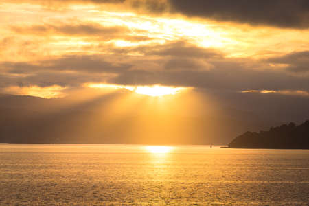 Stunning landscape sunrise  in the morning. Golden light go through the cloud to the mountain and sea.の写真素材