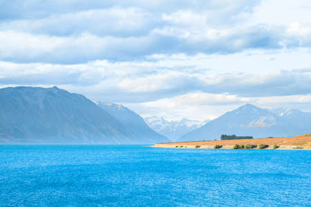 Beautiful scene of blue lake and yellow grassland with mount cook beside lake Tekapo before sunset.の写真素材