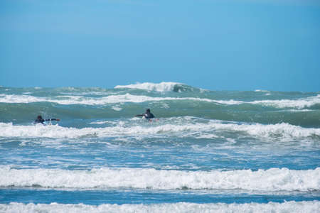 People enjoy their activities at the beautiful beach on a sunny blue sky day.の写真素材