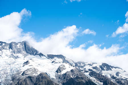 Stunning snow on the rocky mountain with blue sky and white clouds.の写真素材