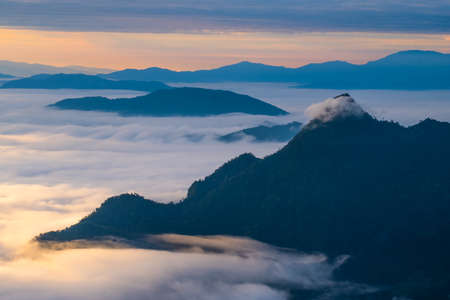 Beautiful sunrise scene at high mountain with yellow clouds and blue sky, Phu chi fah Chiangrai Thailandの写真素材