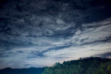Beautiful night scape with dark blue sky with a lot of star white cloud and the green mountain. View from the village in the forest at the north part of Thailand.の写真素材